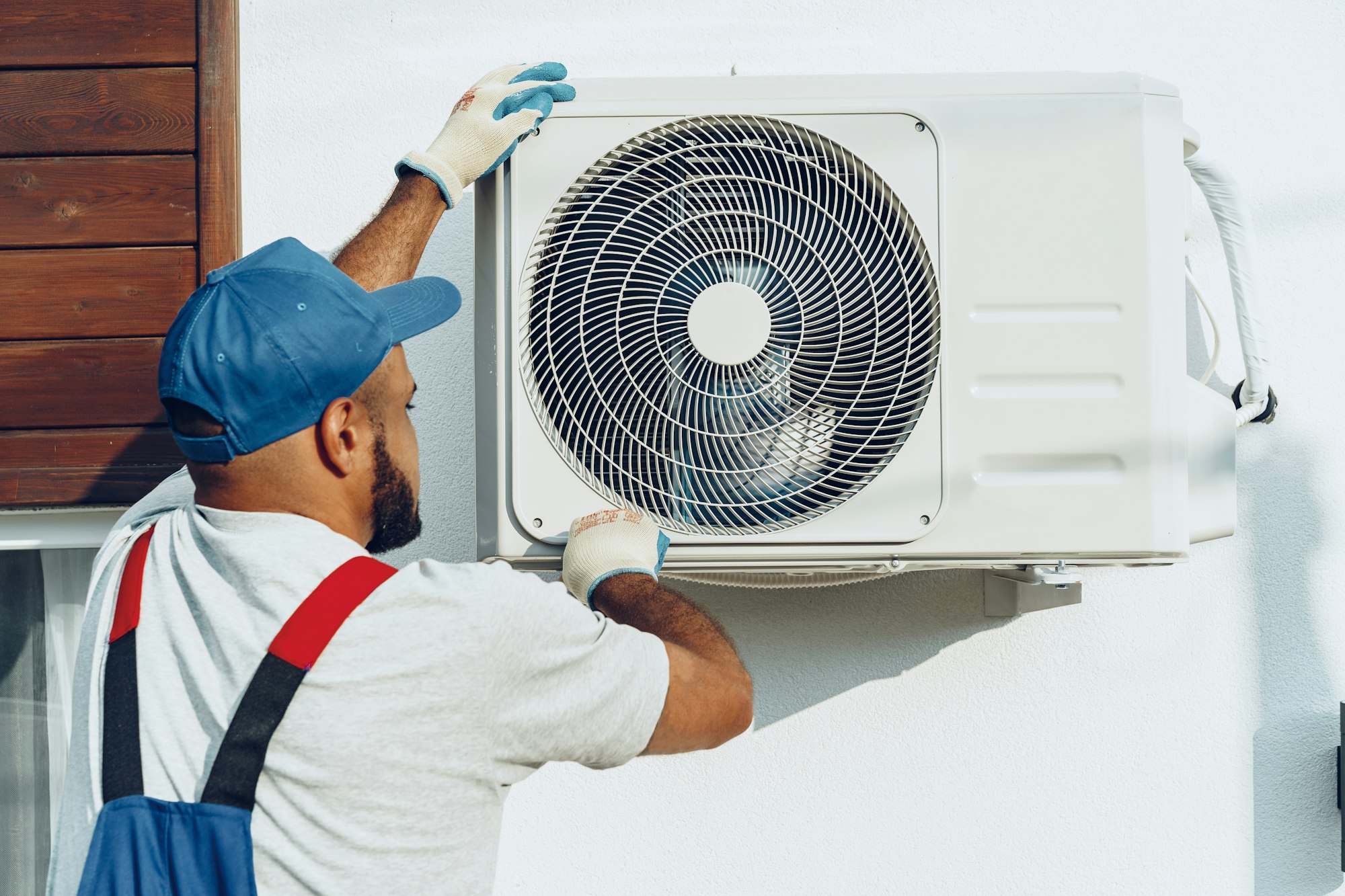 Repairman in uniform installing the outside unit of air conditioner
